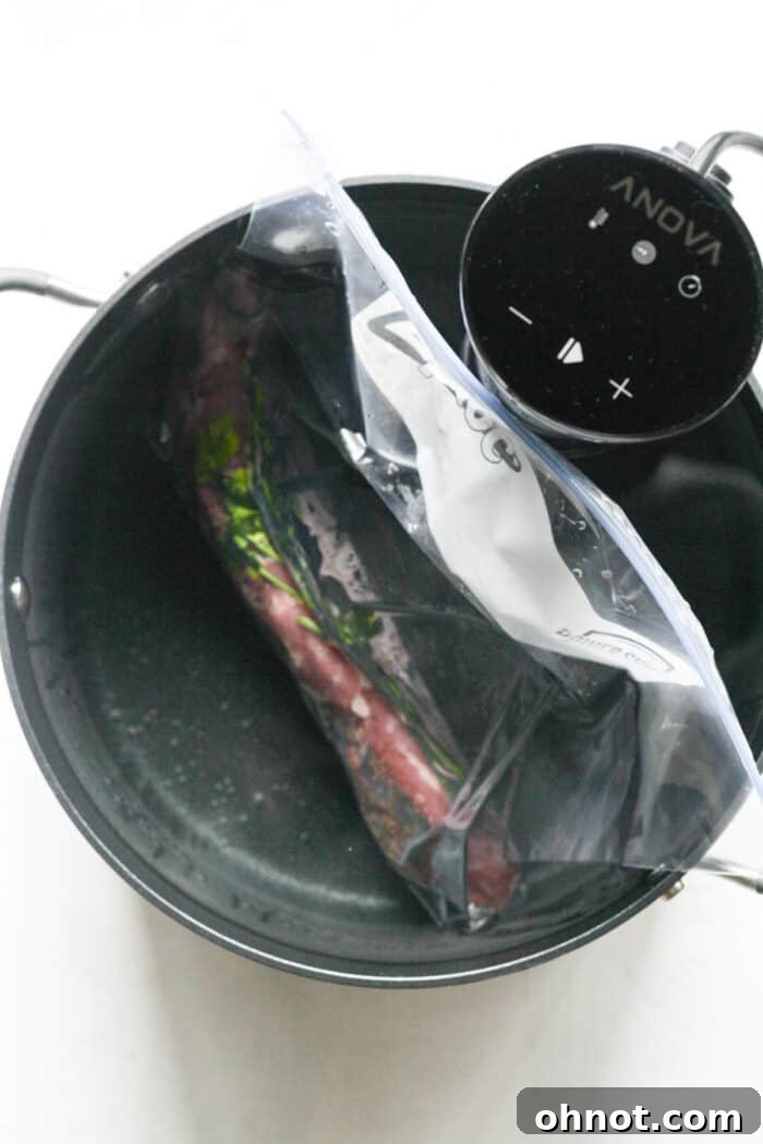 Pork tenderloin sealed in a bag, submerged in a pot of water with a sous vide cooker.