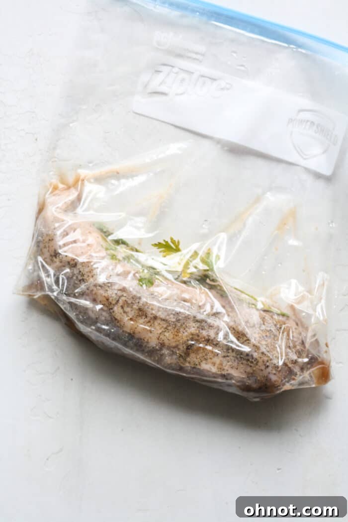 Cooked pork tenderloin removed from the sous vide bag, with herbs visible.