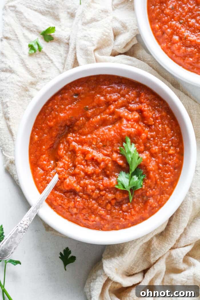 A bowl of creamy, steaming gluten-free tomato soup garnished with fresh herbs, perfect for a cozy meal.