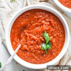 Gluten-free tomato soup in a white bowl, garnished with fresh herbs, ready to be served.