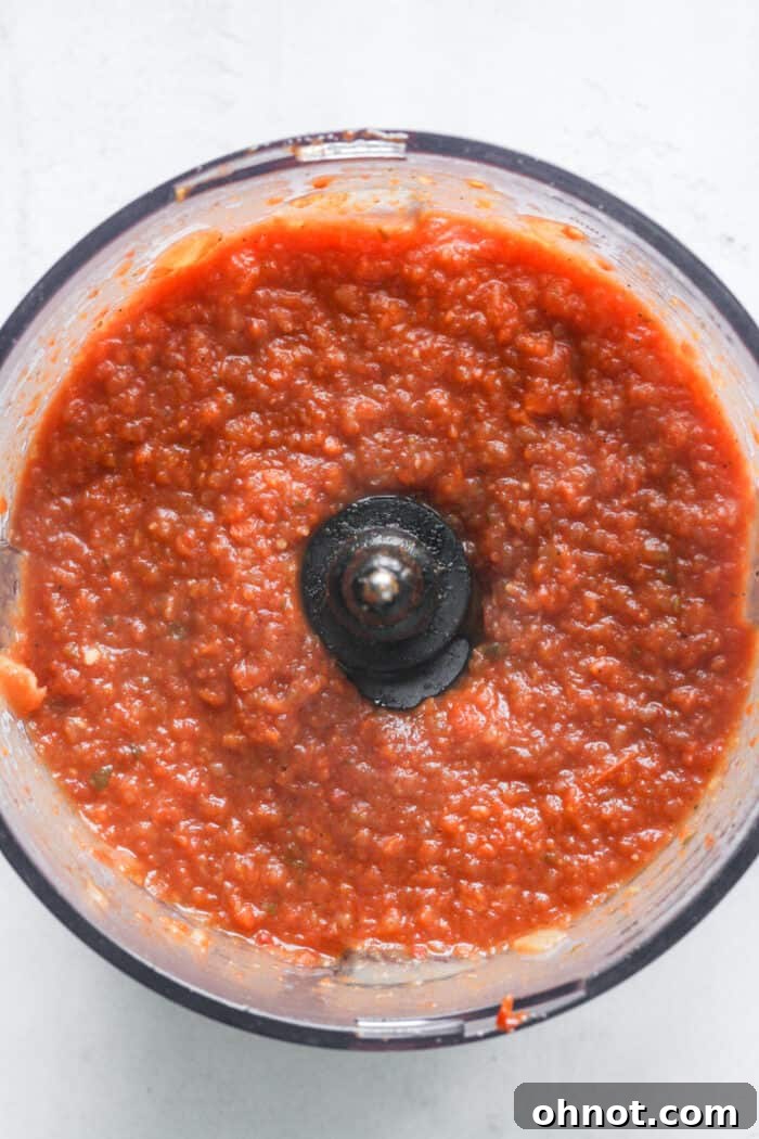 Smooth, blended tomato soup in a food processor, showcasing its creamy texture.