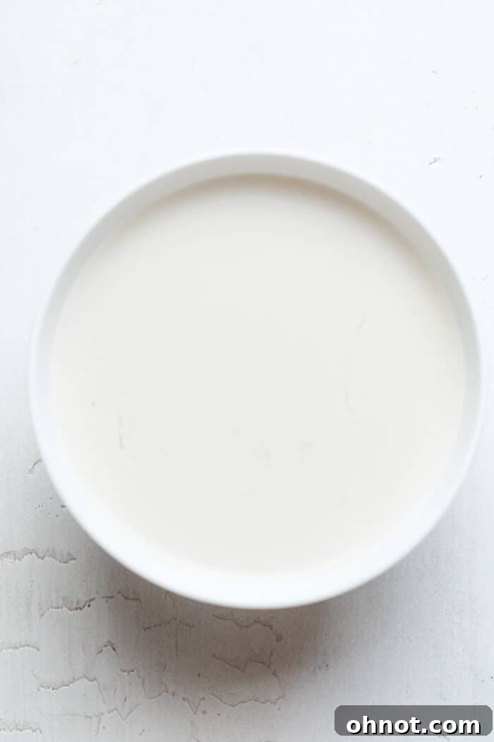 Almond milk in a white bowl before mixing with vinegar.