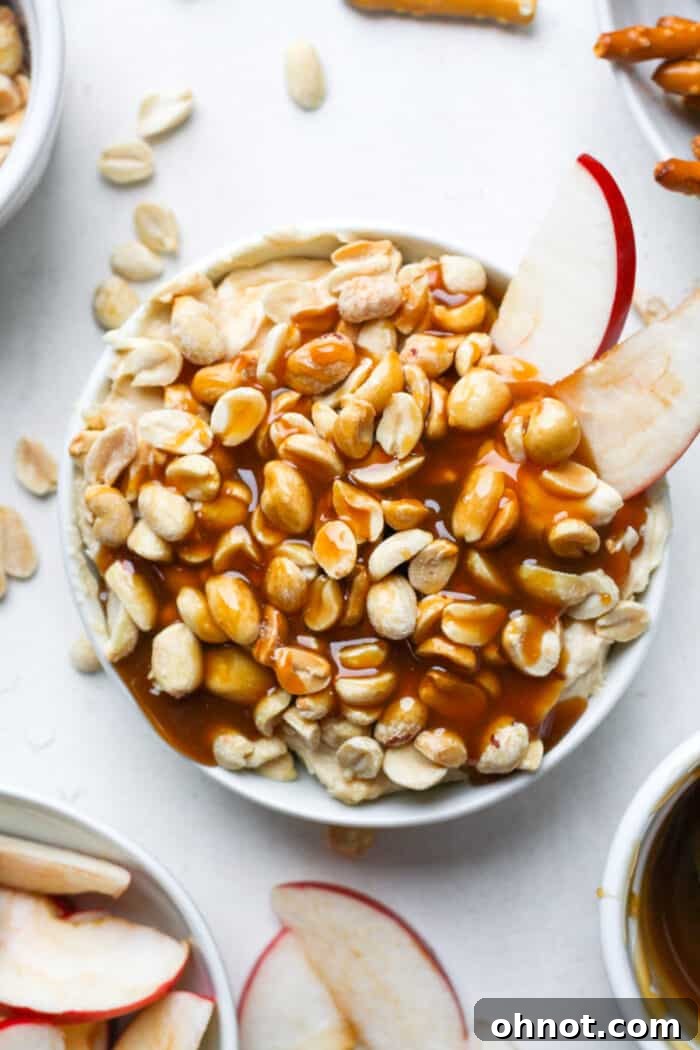 A beautiful white bowl brimming with creamy caramel apple dip, surrounded by perfectly sliced red and green apples, inviting guests to dip and enjoy.