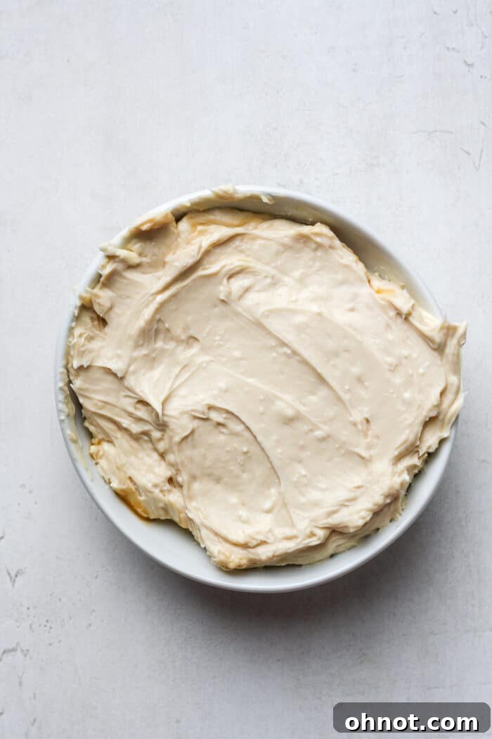 The smoothly blended sweet cream cheese and caramel mixture meticulously transferred to a pristine white bowl, forming the perfect base for the dip.