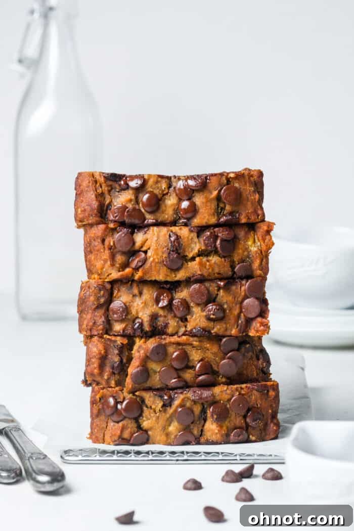 Close-up of a perfectly baked, golden-brown vegan gluten-free banana bread slice on a cooling rack, showcasing its moist texture and chocolate chips.