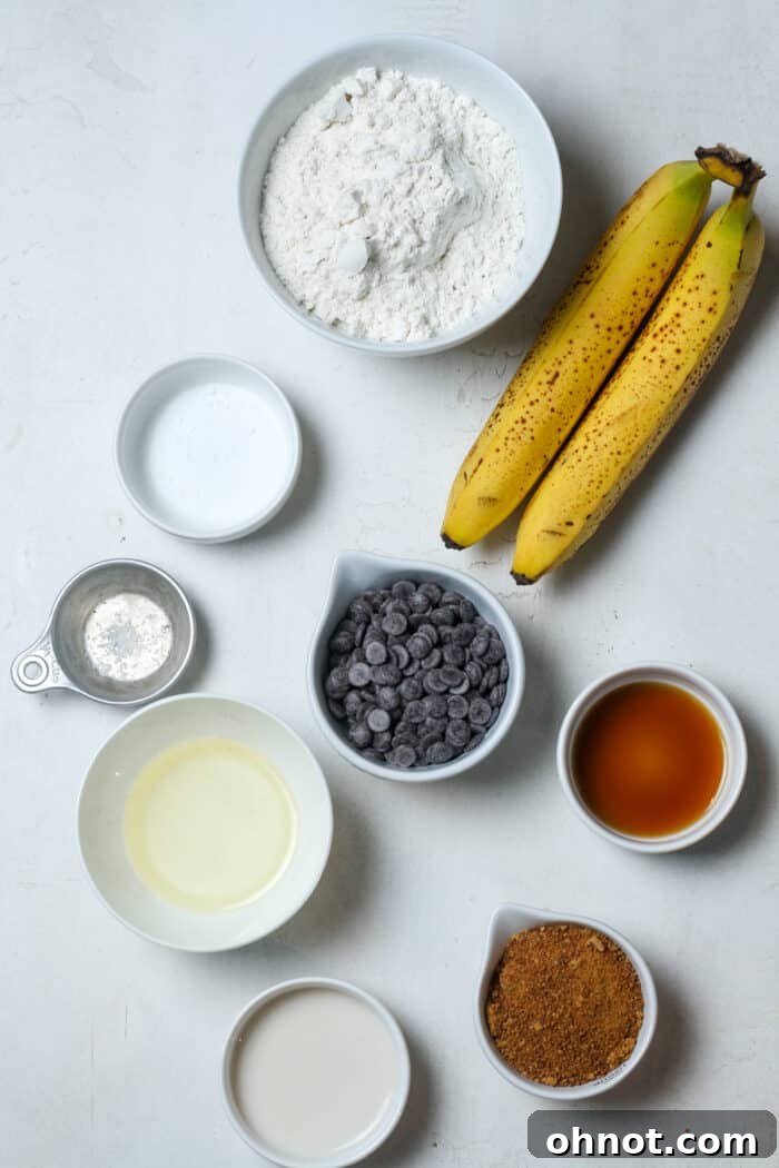 Various ingredients for vegan chocolate chip banana bread, including ripe bananas and white bowls of dry ingredients, laid out for baking prep.