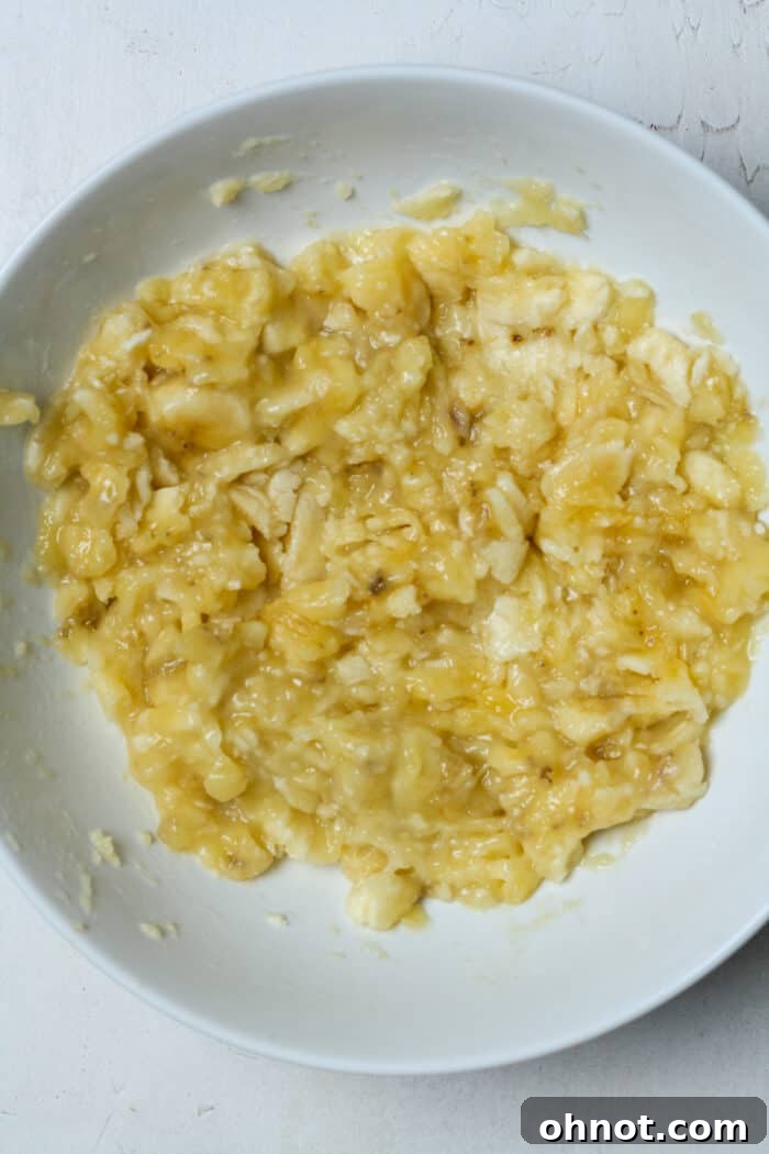 Perfectly mashed ripe bananas in a white bowl, ready for mixing.