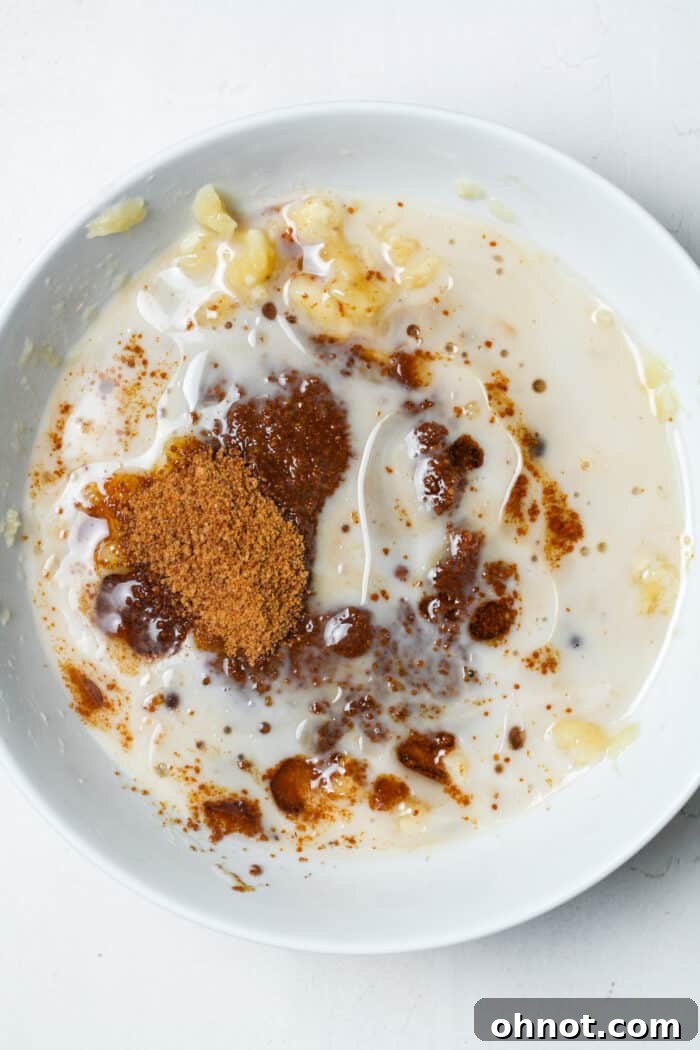 Wet ingredients including melted coconut oil and milk in a white bowl, before mixing.