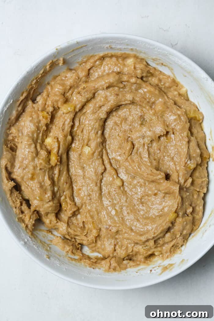 Thick, combined banana bread batter in a large white mixing bowl, ready for chocolate chips.