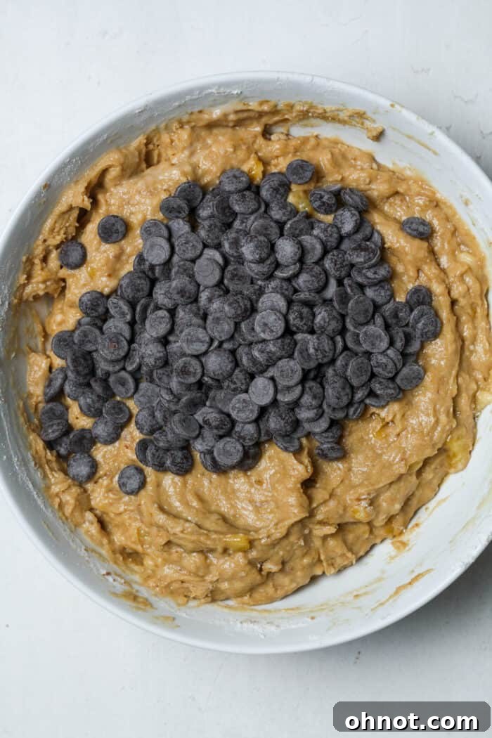 Dark chocolate chips being folded into the thick banana bread batter.