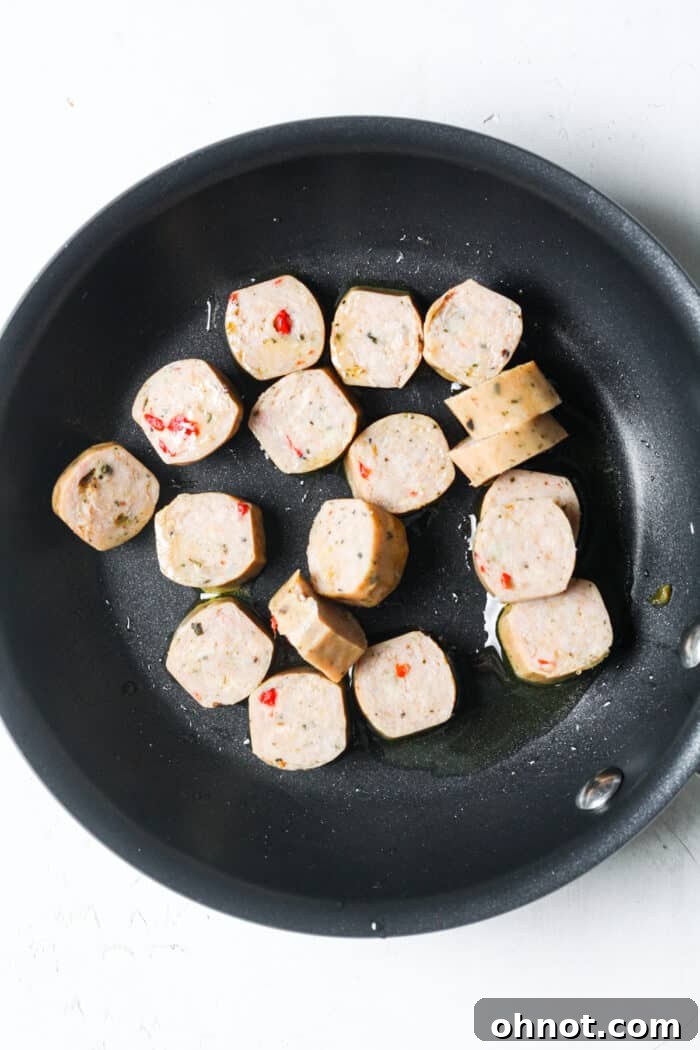 Sliced sausage browning in a skillet with olive oil