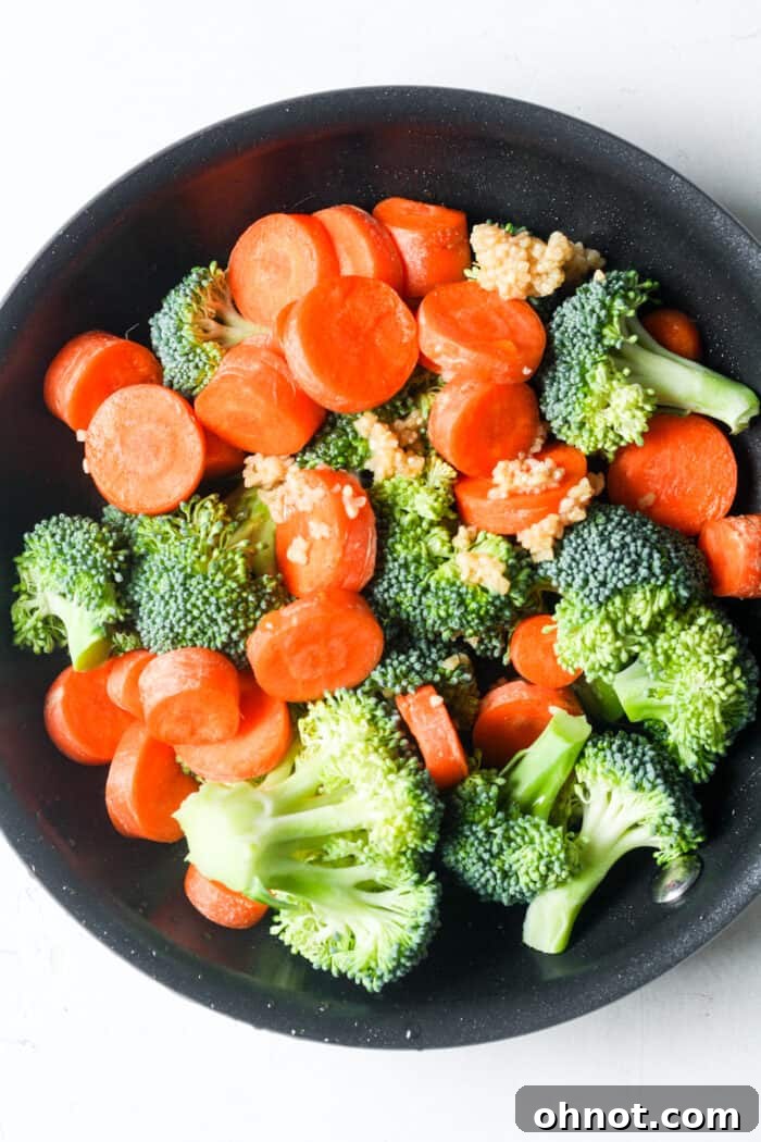 Garlic, broccoli florets, and sliced carrots stir-frying in a skillet