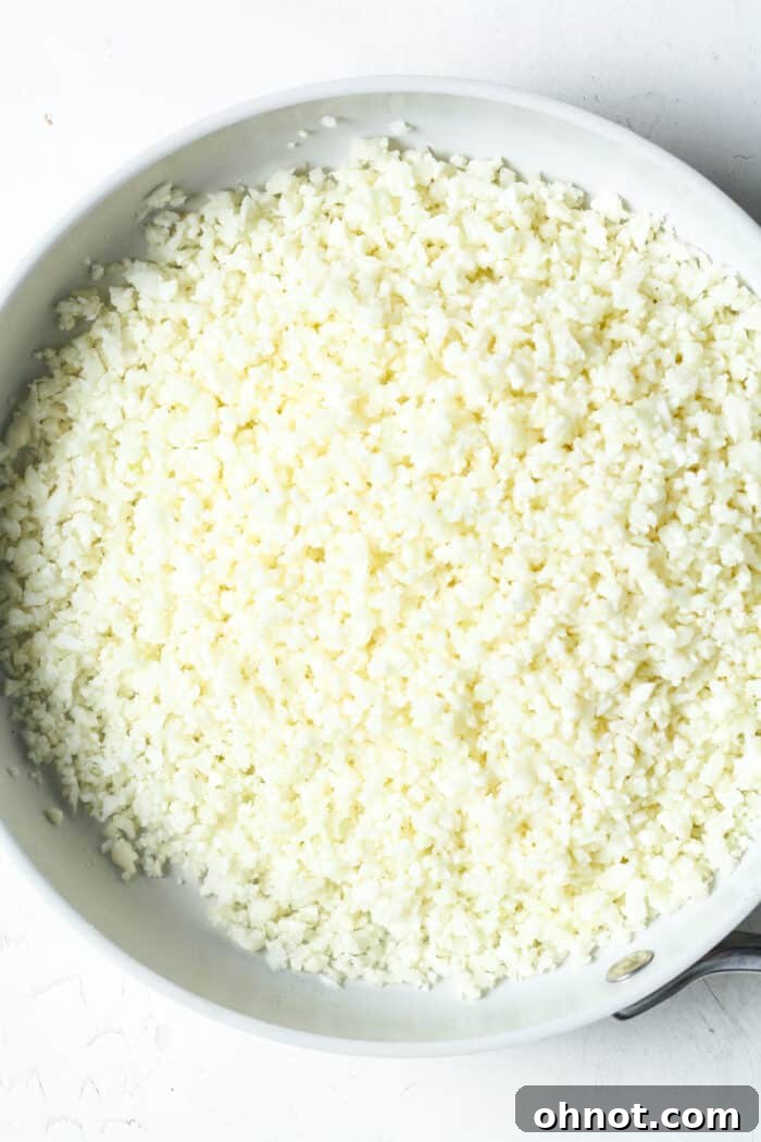 Cauliflower rice cooking in a separate skillet with olive oil