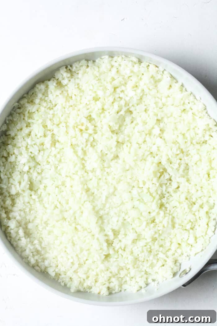 Close-up of cauliflower rice being stirred in a skillet