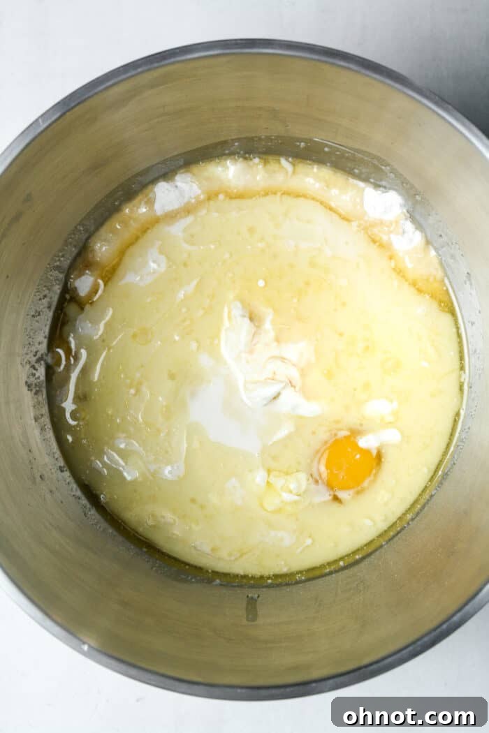 Wet ingredients including eggs, milk, and sour cream added to the dry mixture in a bowl.