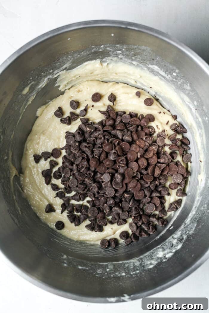 Dark chocolate chips being gently folded into the muffin batter.