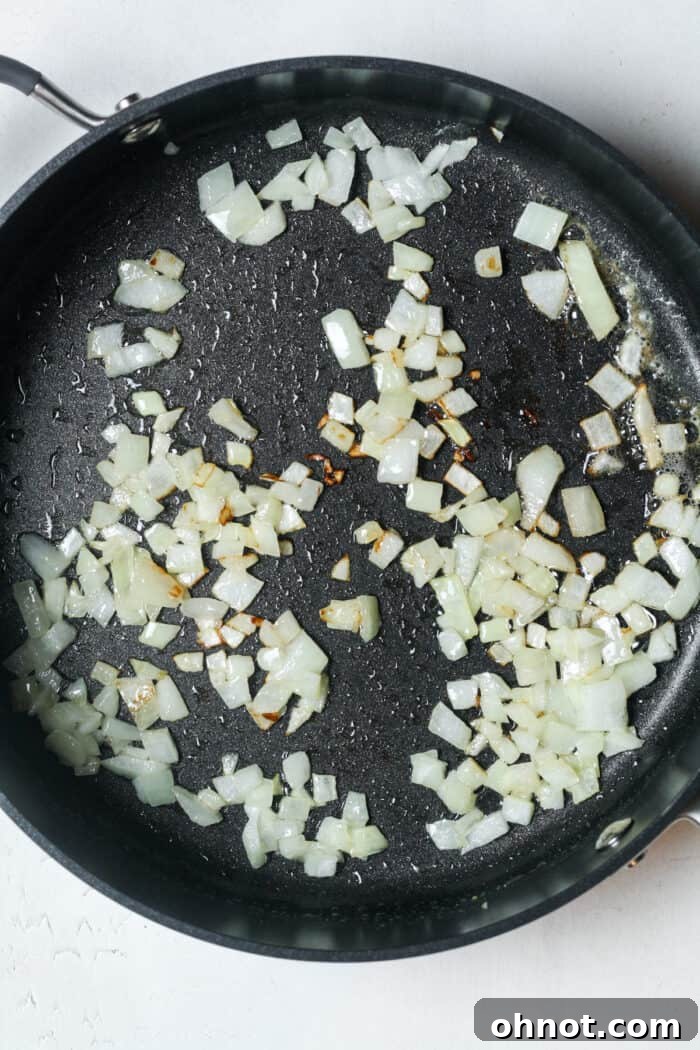 Softened, translucent onions gently cooked to perfection in a skillet, ready for the next step.