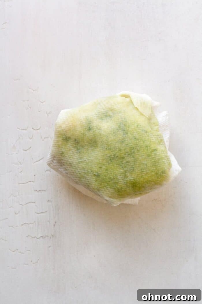 Grated zucchini being wrapped in a paper towel, demonstrating the technique for squeezing out excess water.