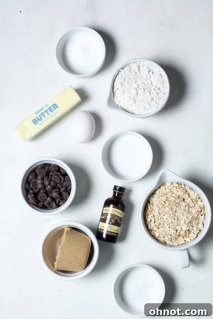 Bowls of rolled oats, butter, brown sugar, and other ingredients for oatmeal chocolate chip bars arranged on a counter.