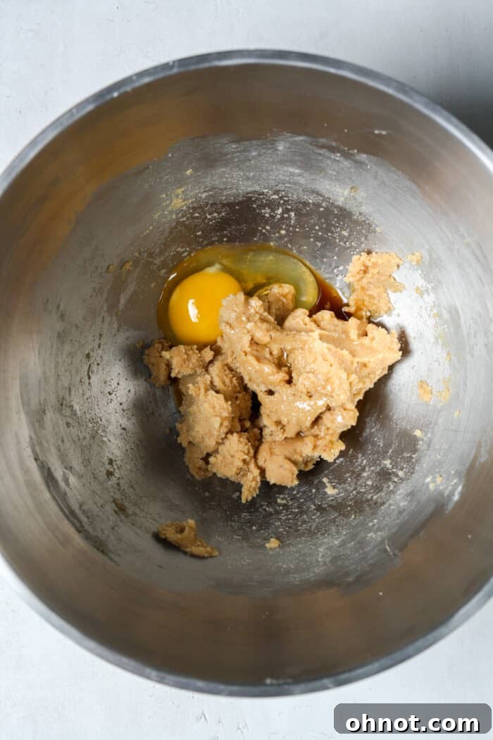 Egg added to the creamed butter and sugar mixture in a bowl.