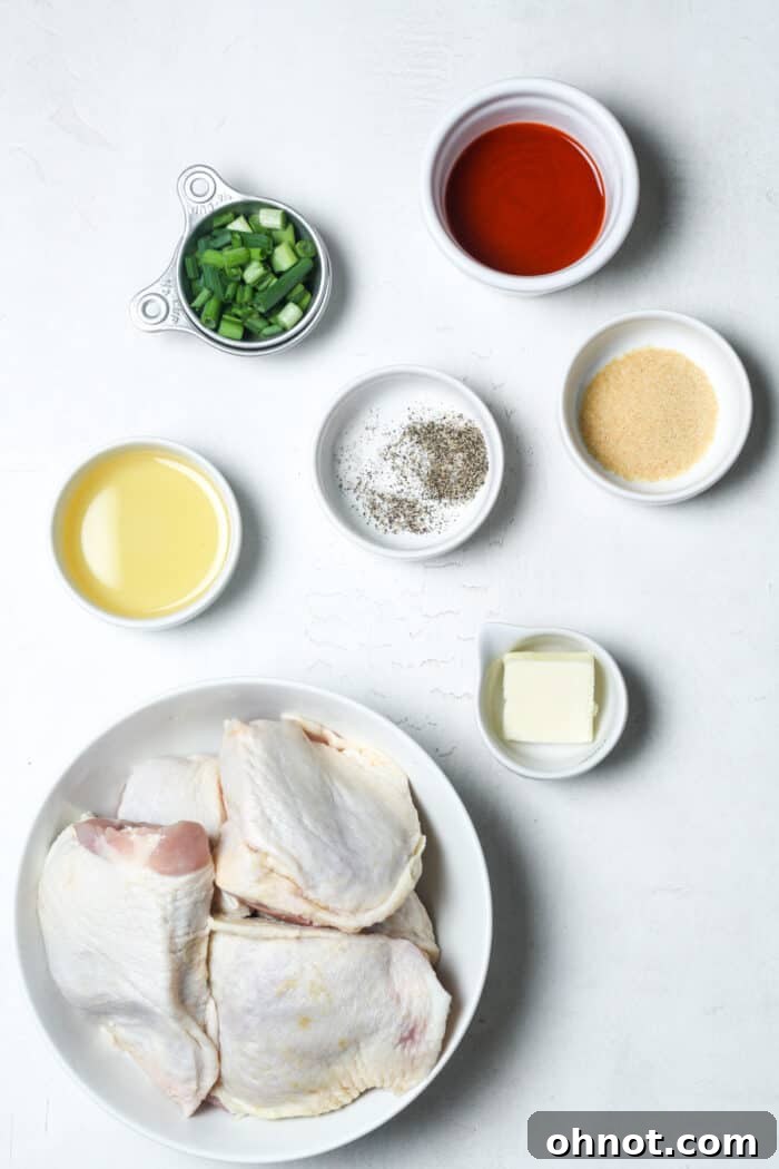 Various ingredients for buffalo chicken thighs, including raw chicken, oil, and spices, laid out in bowls.