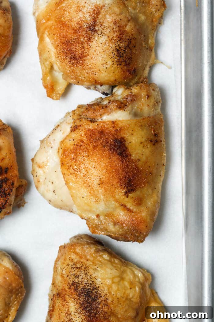 Crispy, oven-baked chicken thighs on a pan, golden brown and perfectly cooked.