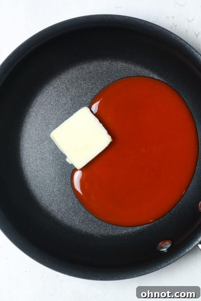 Buffalo hot sauce and butter melting together in a skillet over low heat.