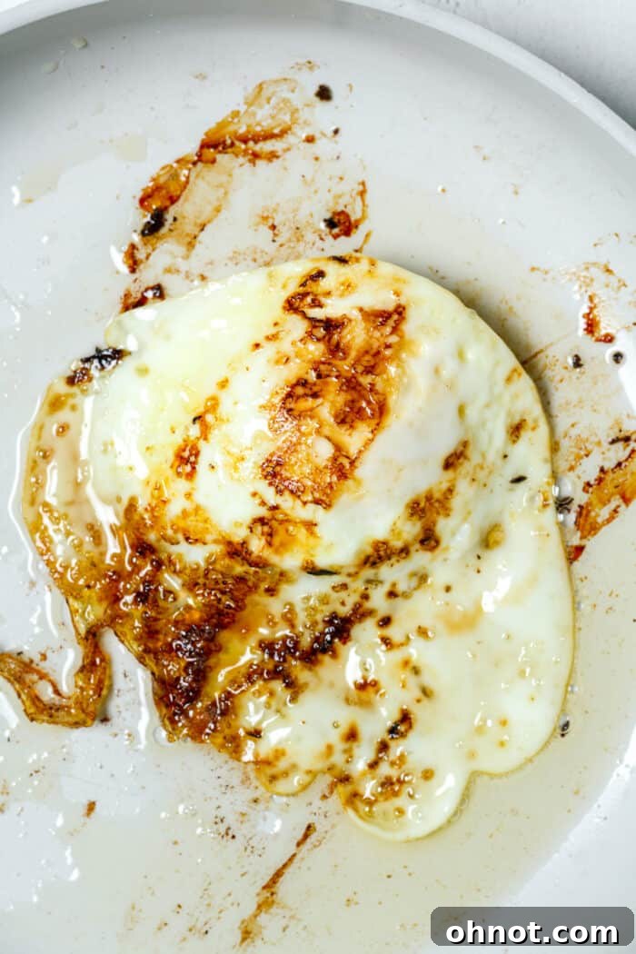 Crispy fried egg in skillet, just flipped