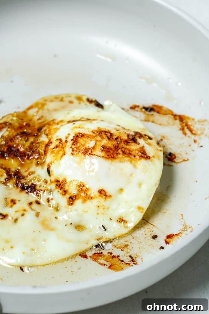 Hard over egg in skillet, showing fully cooked yolk