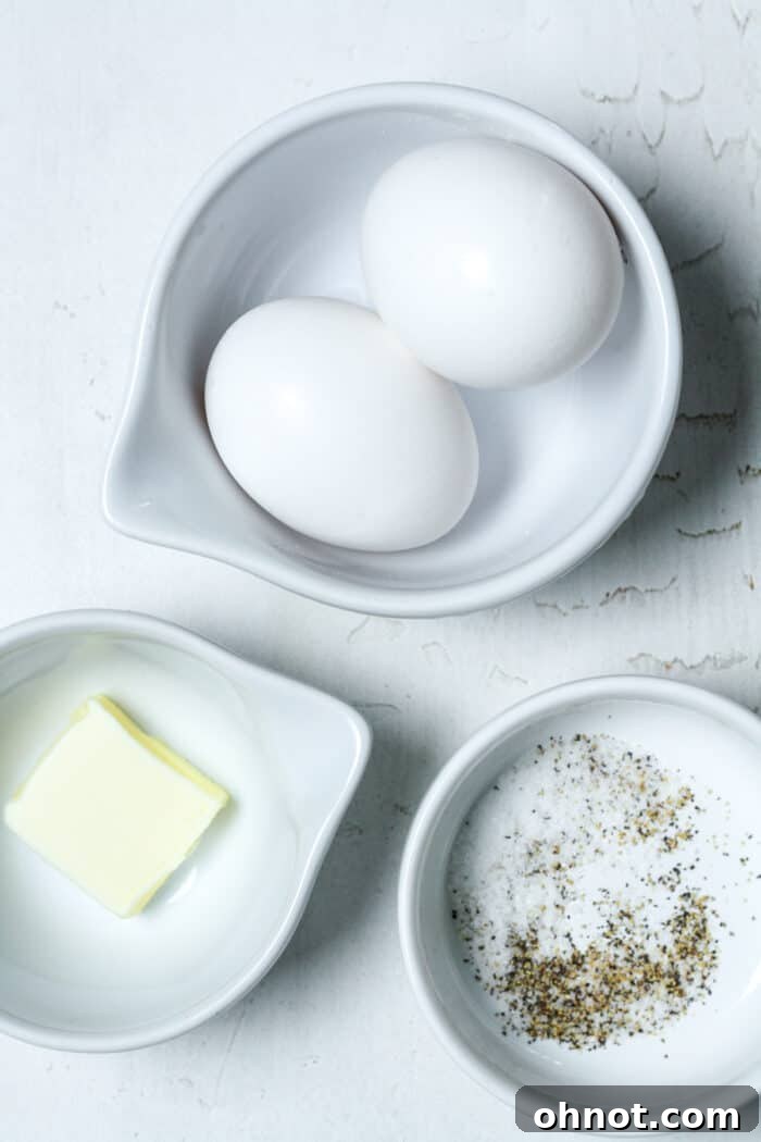 Eggs, butter, salt and pepper in small white bowls ready for cooking