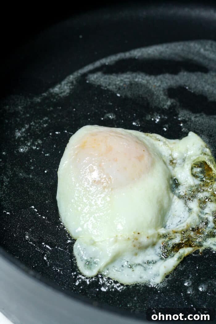 Puffed up egg in pan, indicating the yolk is fully cooked