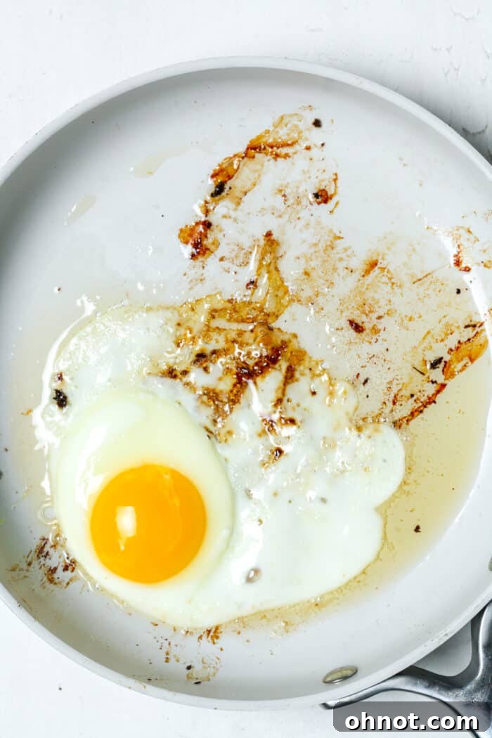 Egg cooking in bacon grease in a hot skillet