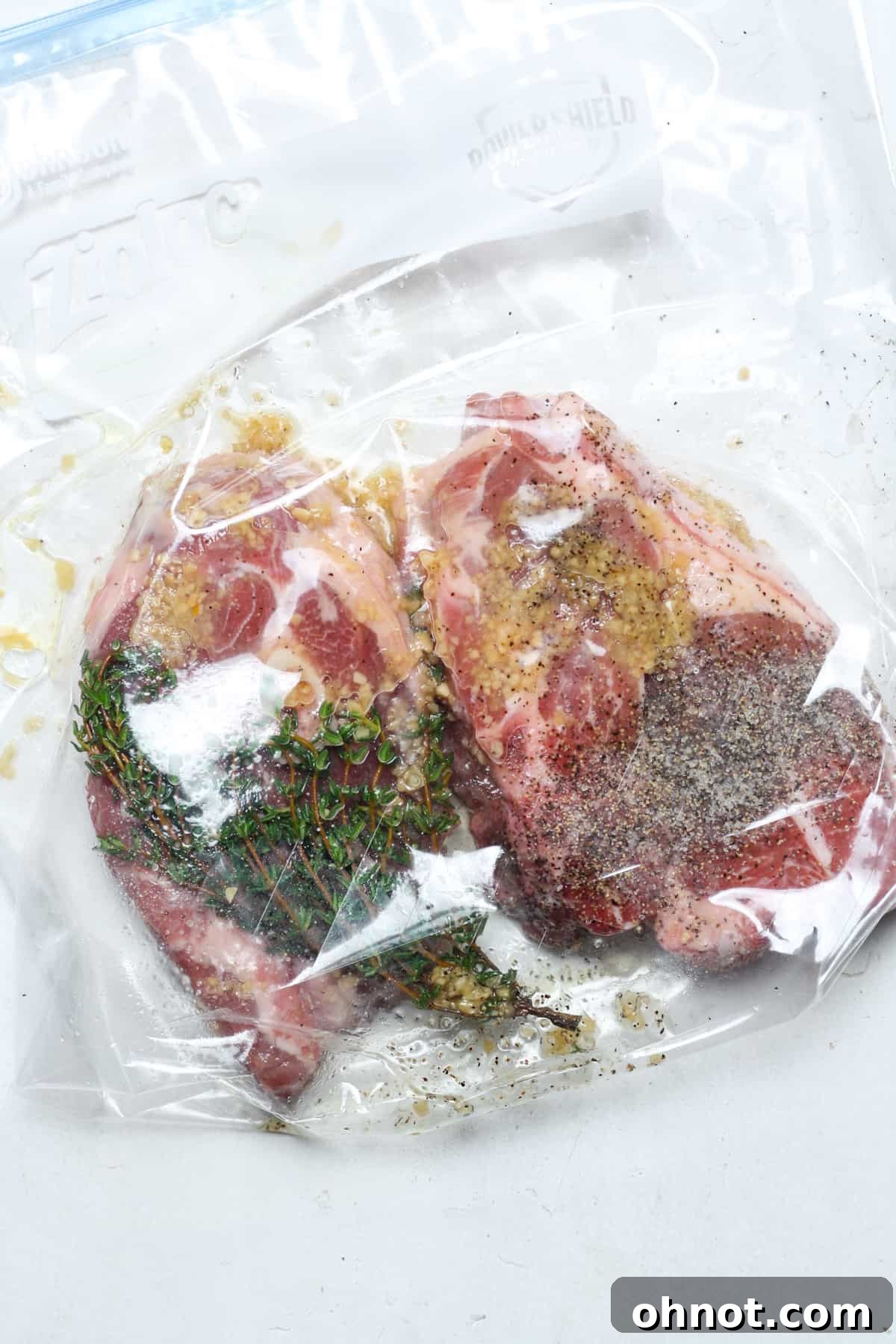 Close-up of lamb chops fully coated in seasonings and rosemary, neatly arranged inside a clear Ziplock bag before the air is removed for sous vide cooking.