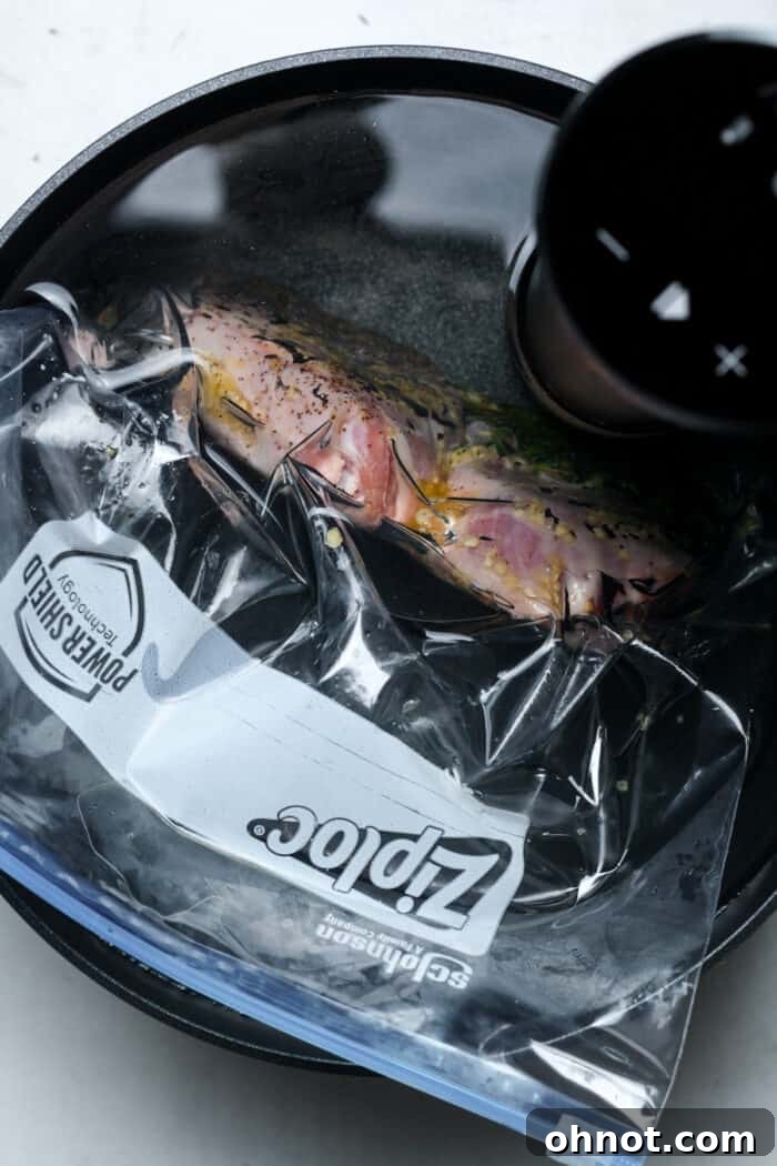 A sealed bag containing seasoned lamb chops is submerged in a clear sous vide water bath, cooking precisely at a controlled temperature.