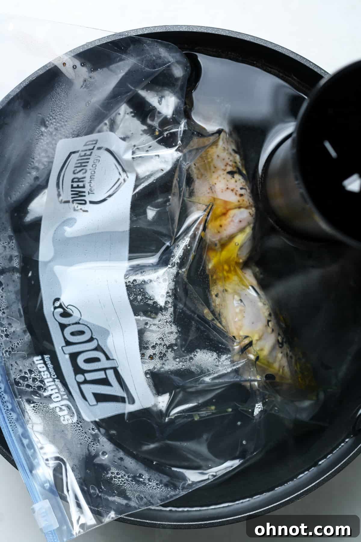 Cooked sous vide lamb chops are removed from the water bath, still inside the sealed bag, maintaining their juices and tenderness.