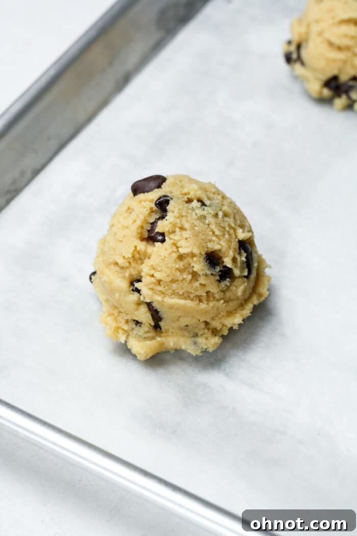 A ball of cookie dough scooped onto a parchment-lined baking pan