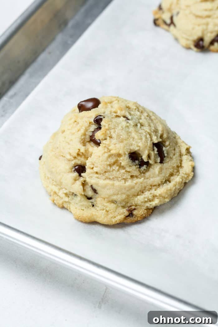 A freshly baked, soft cookie on a baking pan with golden edges