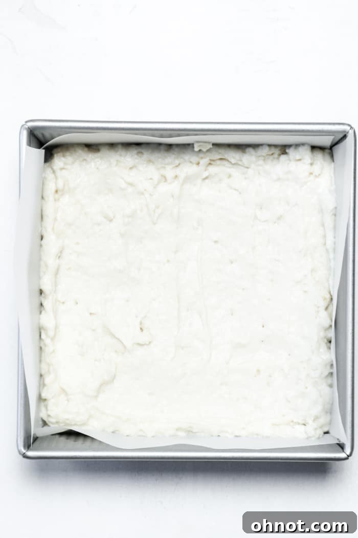 The first layer of vegan coffee cake batter neatly spread in a parchment-lined baking pan, forming the base of the cake.