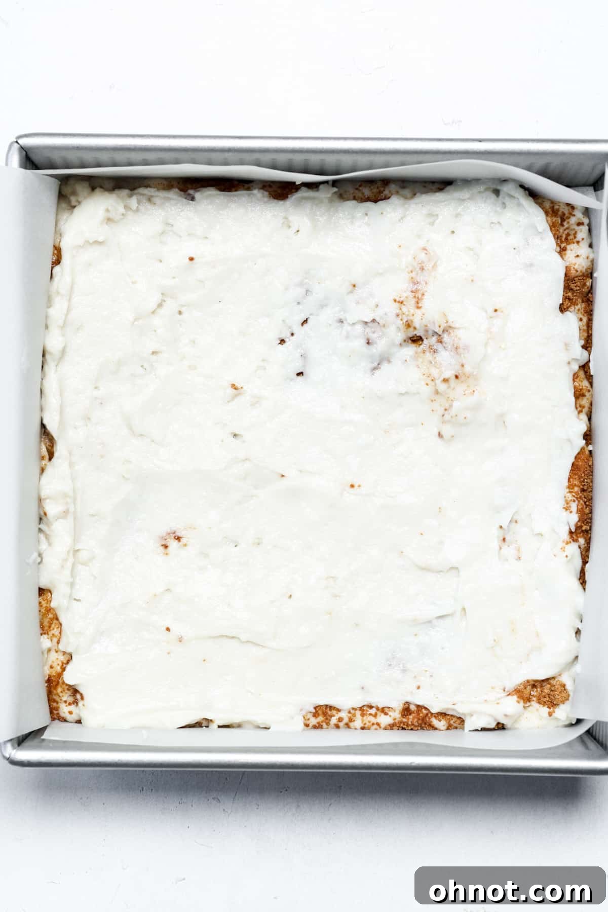Two distinct layers of vegan coffee cake batter and cinnamon swirl visible in a baking pan, showing the intricate layering.
