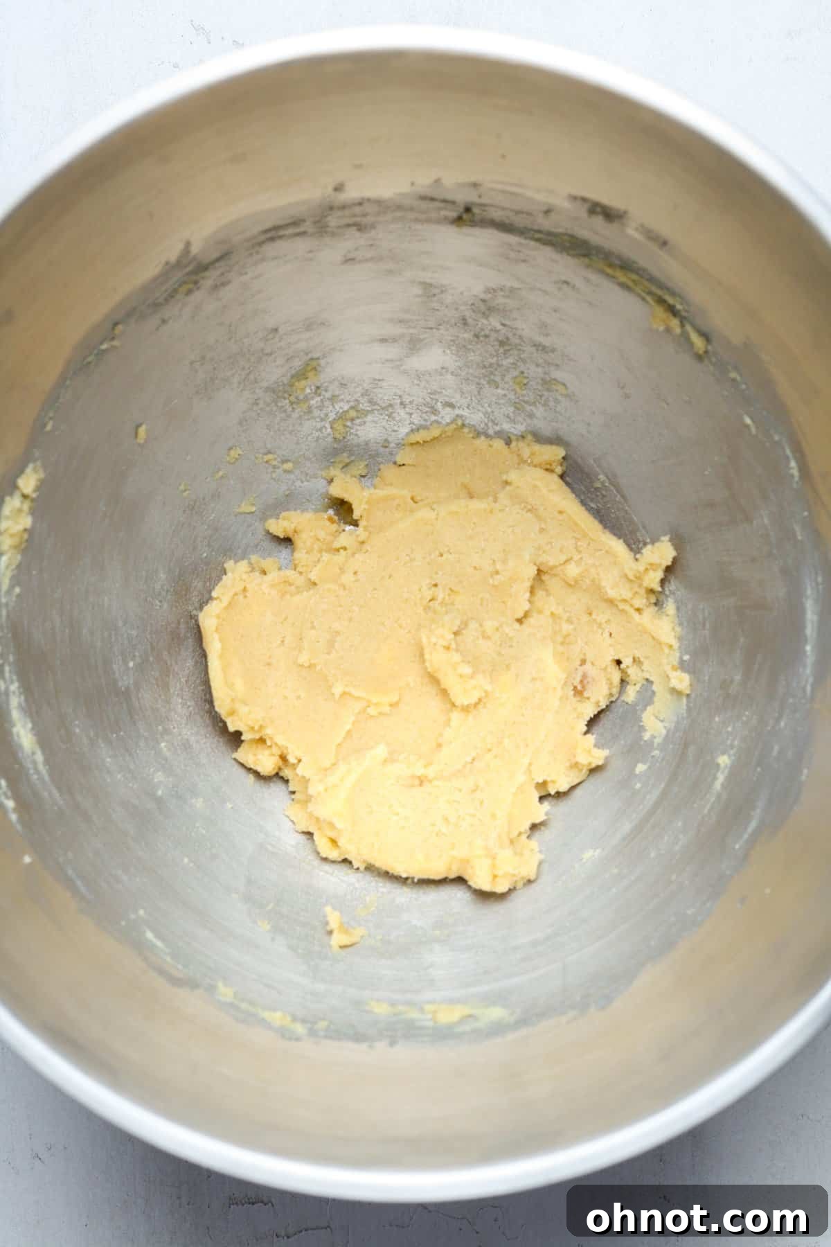 The butter and sugar mixture after being thoroughly creamed, appearing light and fluffy in the bowl.