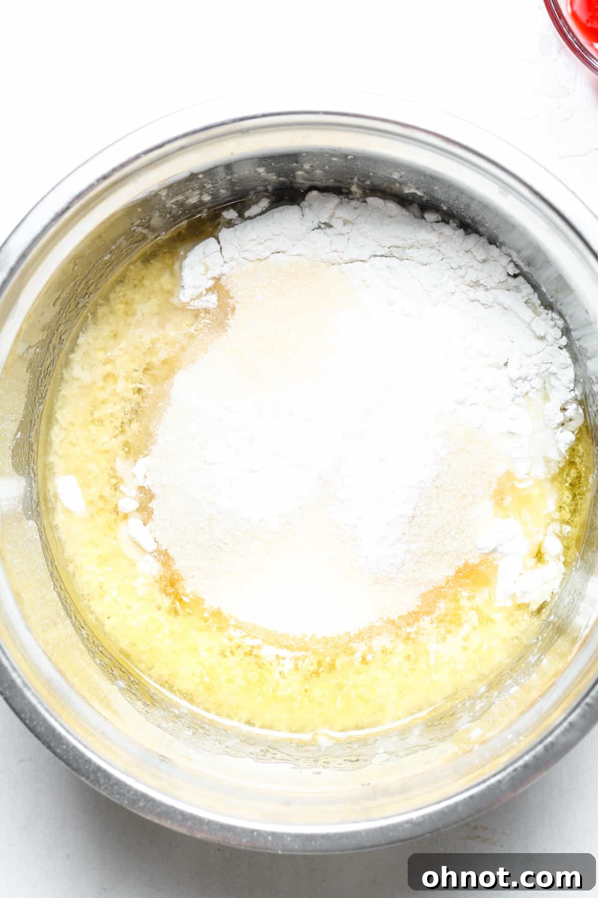 Flour, sugar, and baking soda added to the wet ingredients in a bowl.