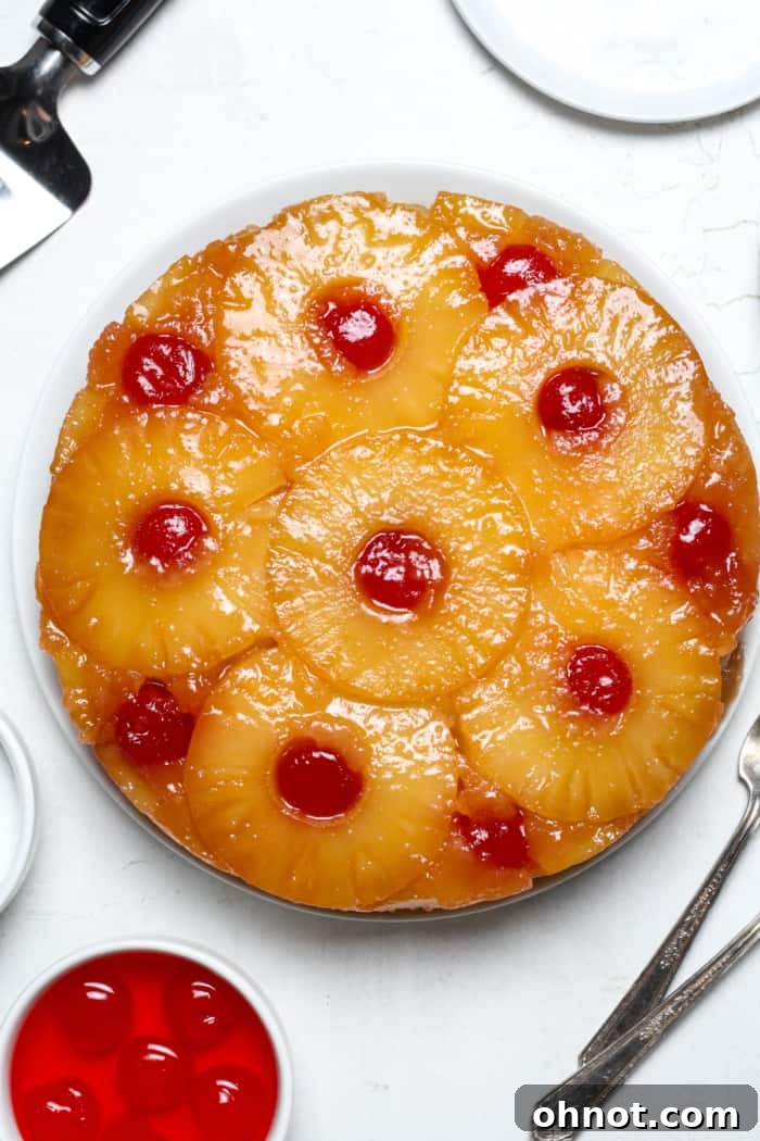 Freshly inverted pineapple upside down cake with cherries on a serving plate.
