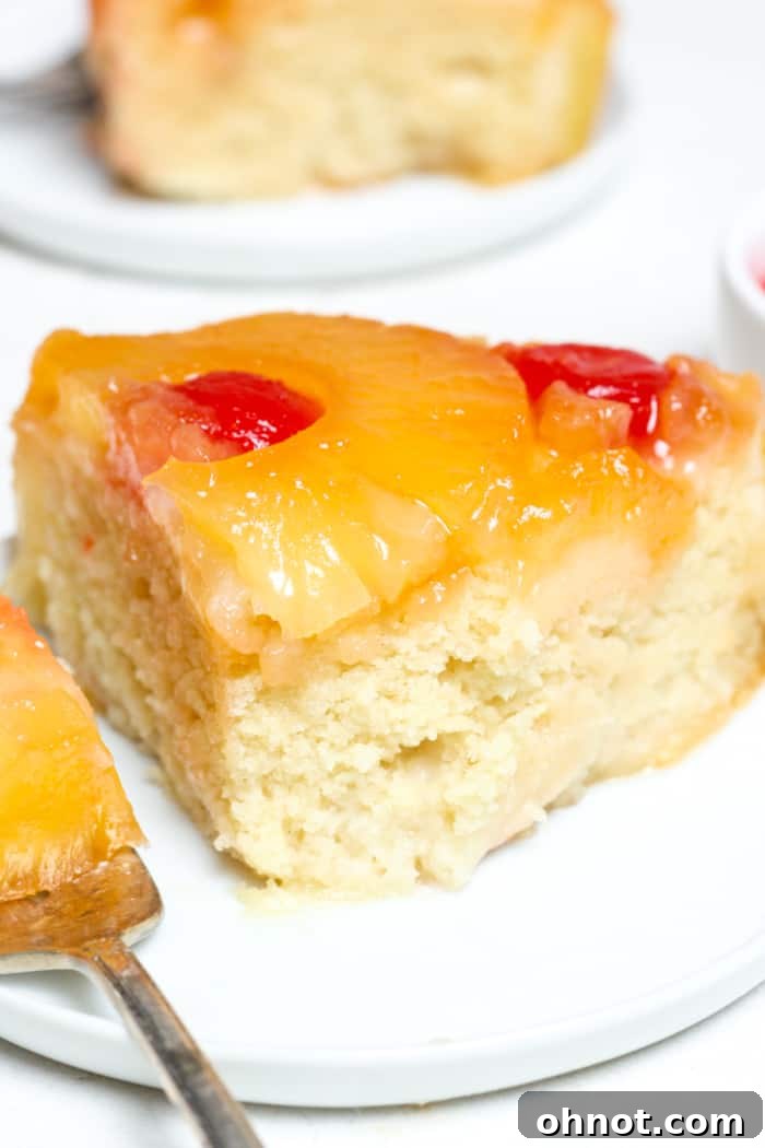 Moist pineapple upside down cake on a white plate, showing the beautiful fruit topping.