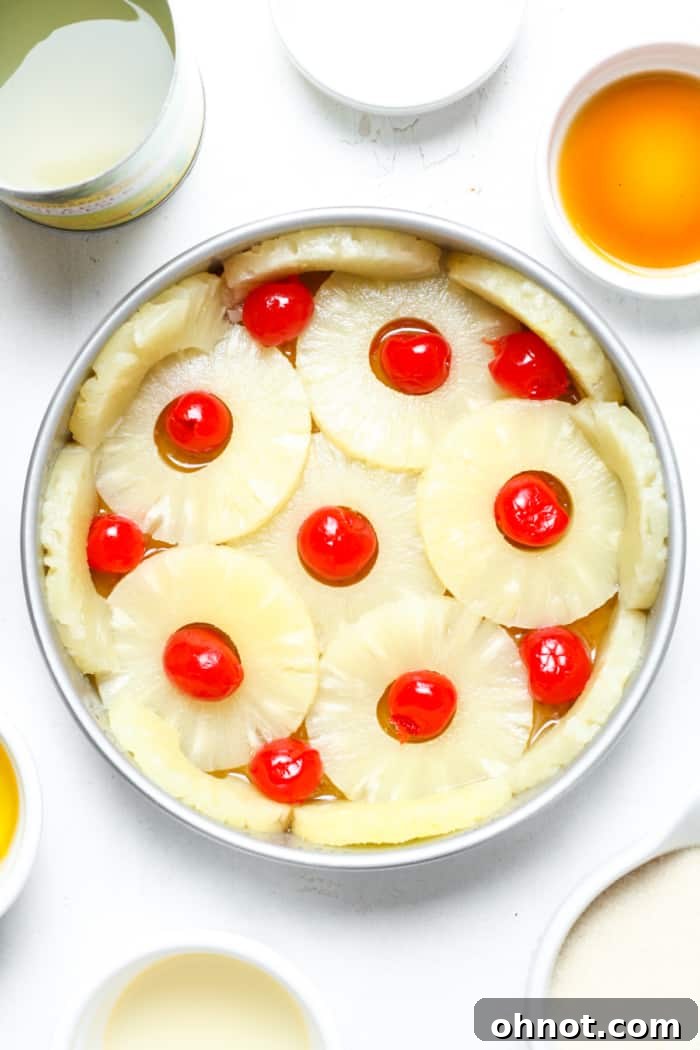 Maraschino cherries placed within the pineapple rings in the cake pan.