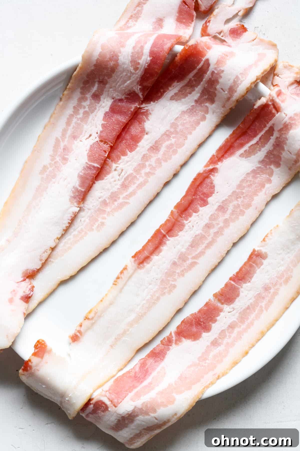 Raw bacon strips neatly arranged on a plate