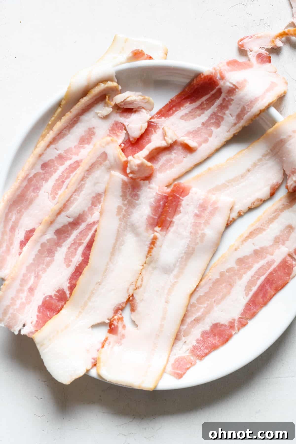 Raw bacon sliced in half, ready for cooking
