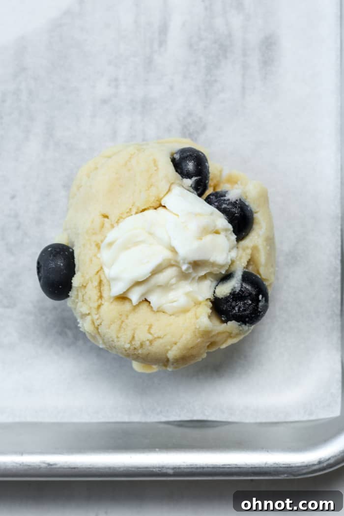 A ball of frozen cream cheese filling placed into the indent of a cookie dough ball.