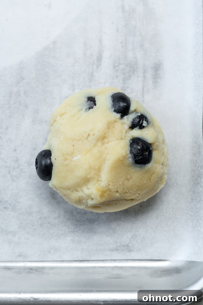 Finished blueberry cookie dough balls, with the cream cheese filling fully enclosed, ready for baking.