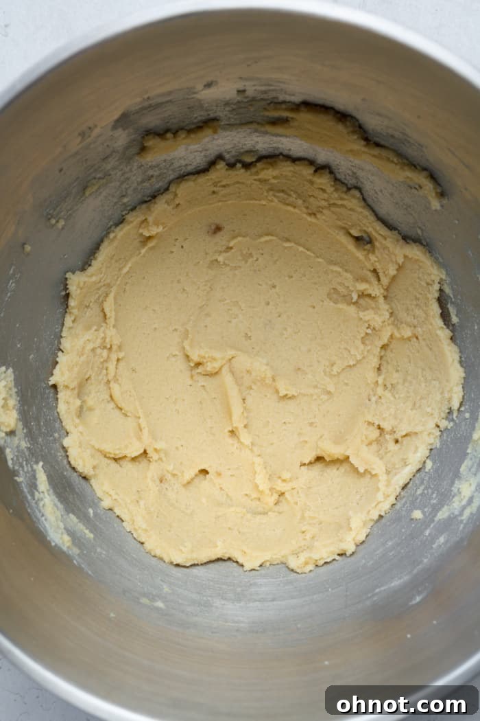 Creamy, pale cookie dough mixture in a stand mixer bowl after butter and sugars have been beaten.