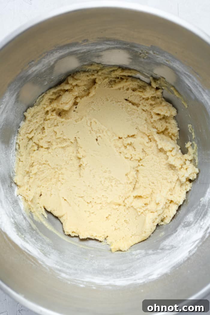 Thick cookie batter in a bowl after flour and baking soda have been mixed in.